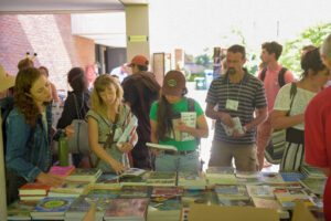 Conference attendees peruse books for sale that are displayed on a table