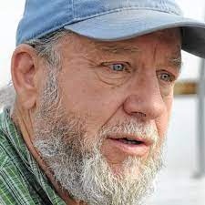 A close up of a man with a beard wearing a blue baseball hat