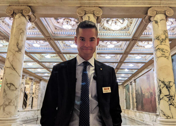 A person in a suit and tie in front of a marble staircase