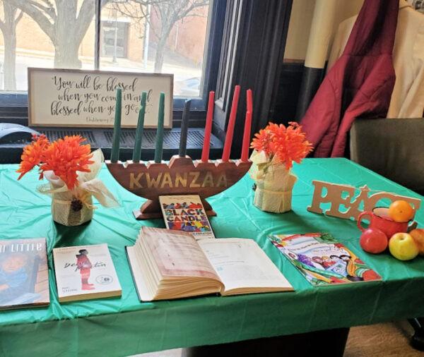 A Kwanzaa kinara on a table with other decorations for the holiday.